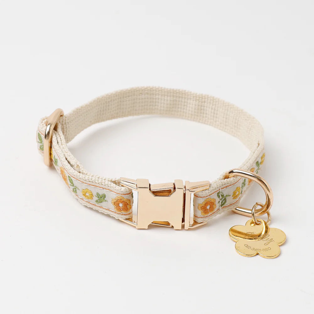 Floral-patterned dog collar with a gold buckle and tag on a white background