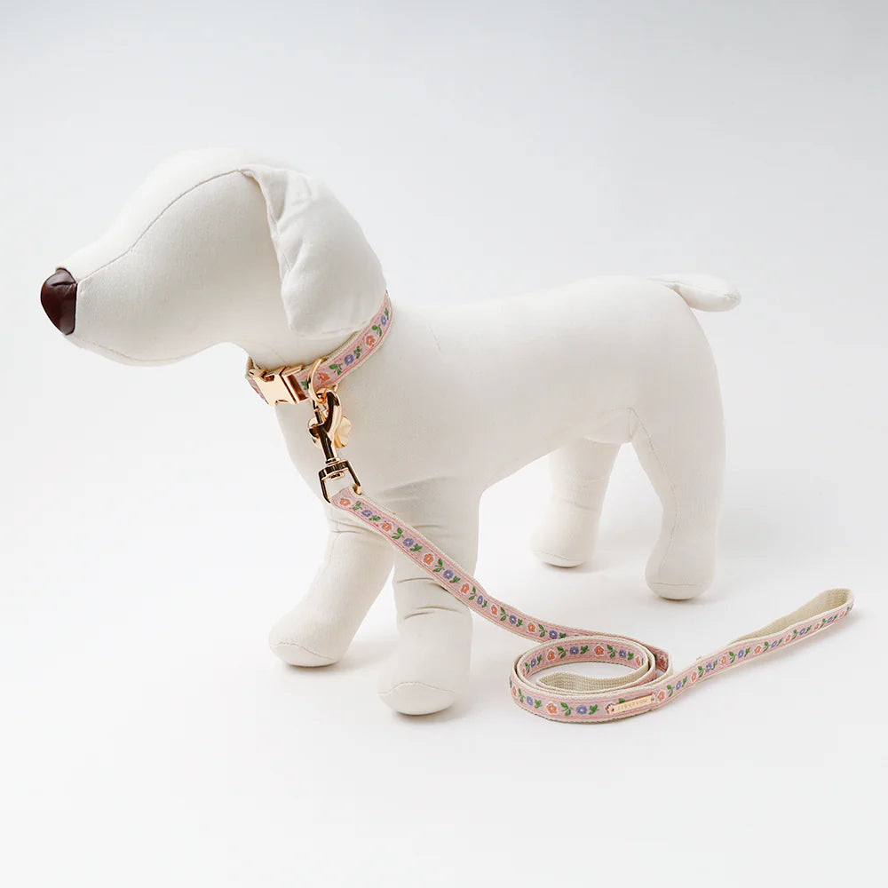 White dog figurine with a floral leash on a white background
