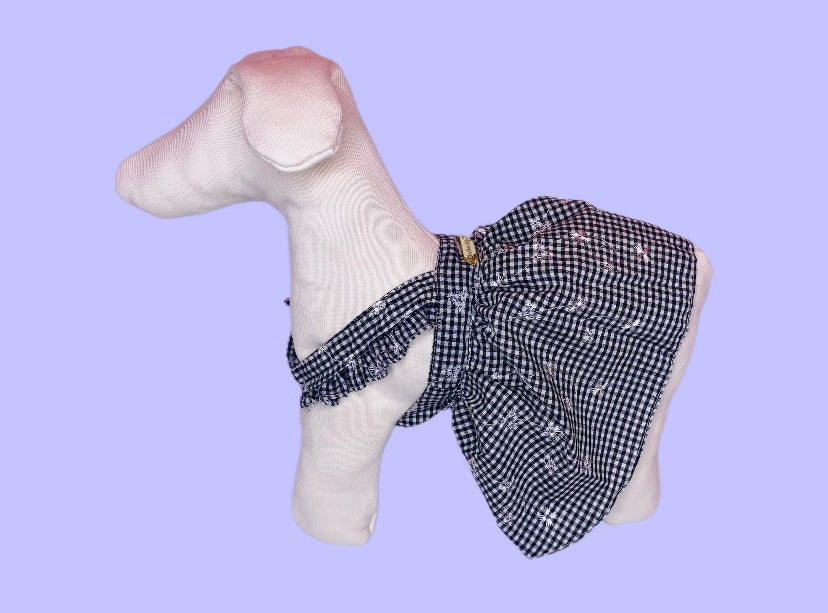 White dog figurine wearing a black and white checkered bow tie on a light purple background